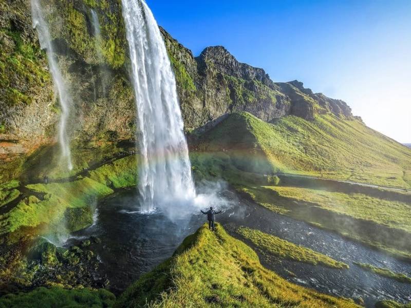 Tourist standing in front of Seljalandsfoss one of the best known waterfalls in southern Iceland The most famoust Icelandic waterfall beautiful amazing landscape from Iceland